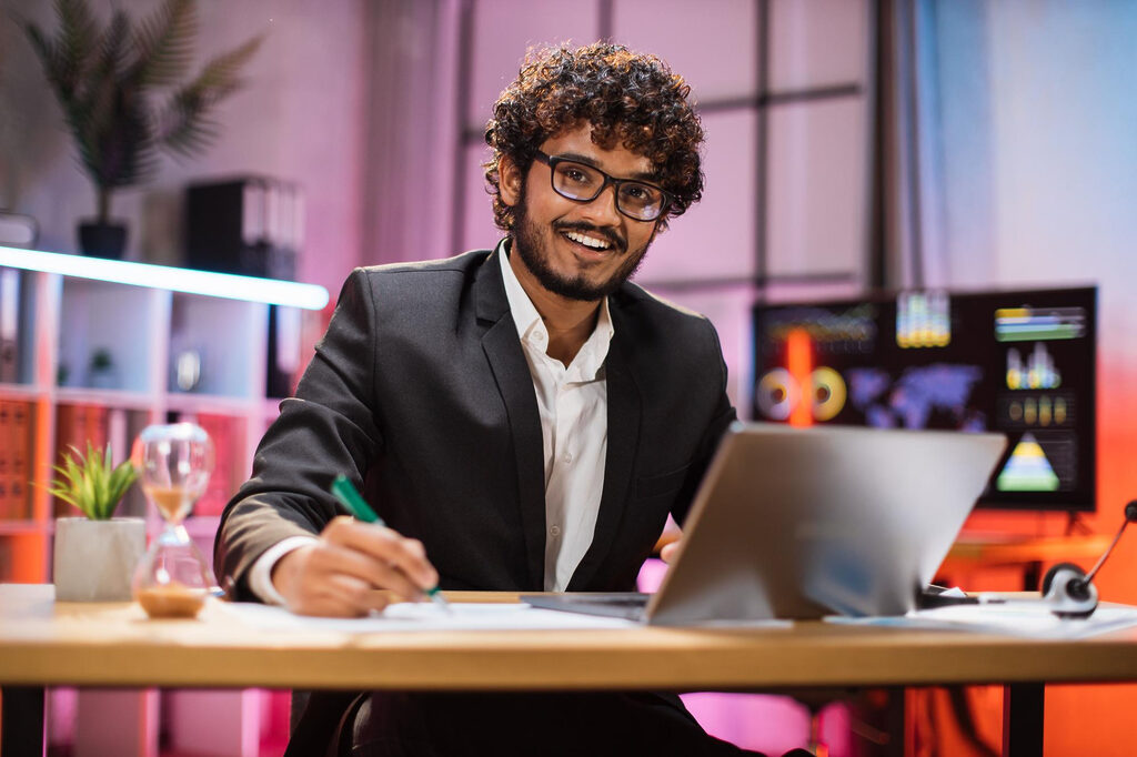 A confident marketer wearing suit, sitting at a desk and working with laptop